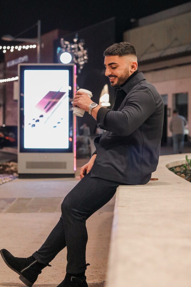 Lachende man ’s avonds in de stad, koffie in de hand