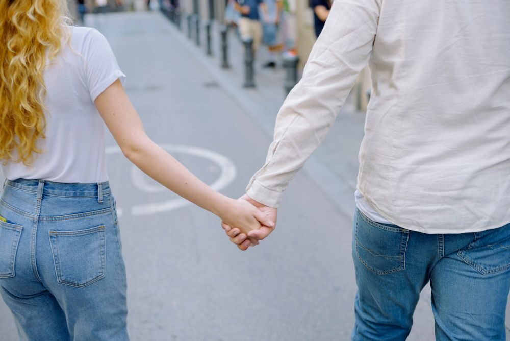 Verstrengelde handen van een stel dat over straat loopt