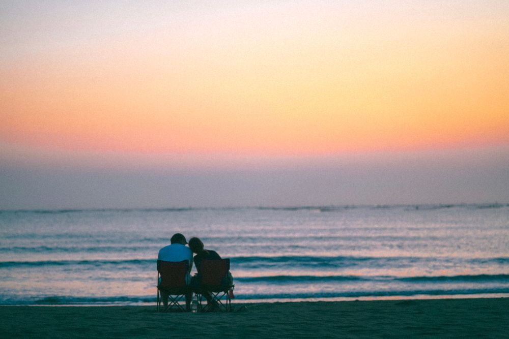 夕暮れのビーチに座るカップル