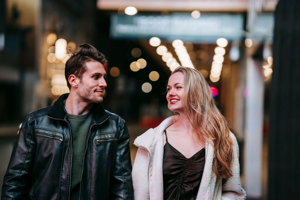 زوجان يتبادلان الابتسام في شارع مضاء مساءً