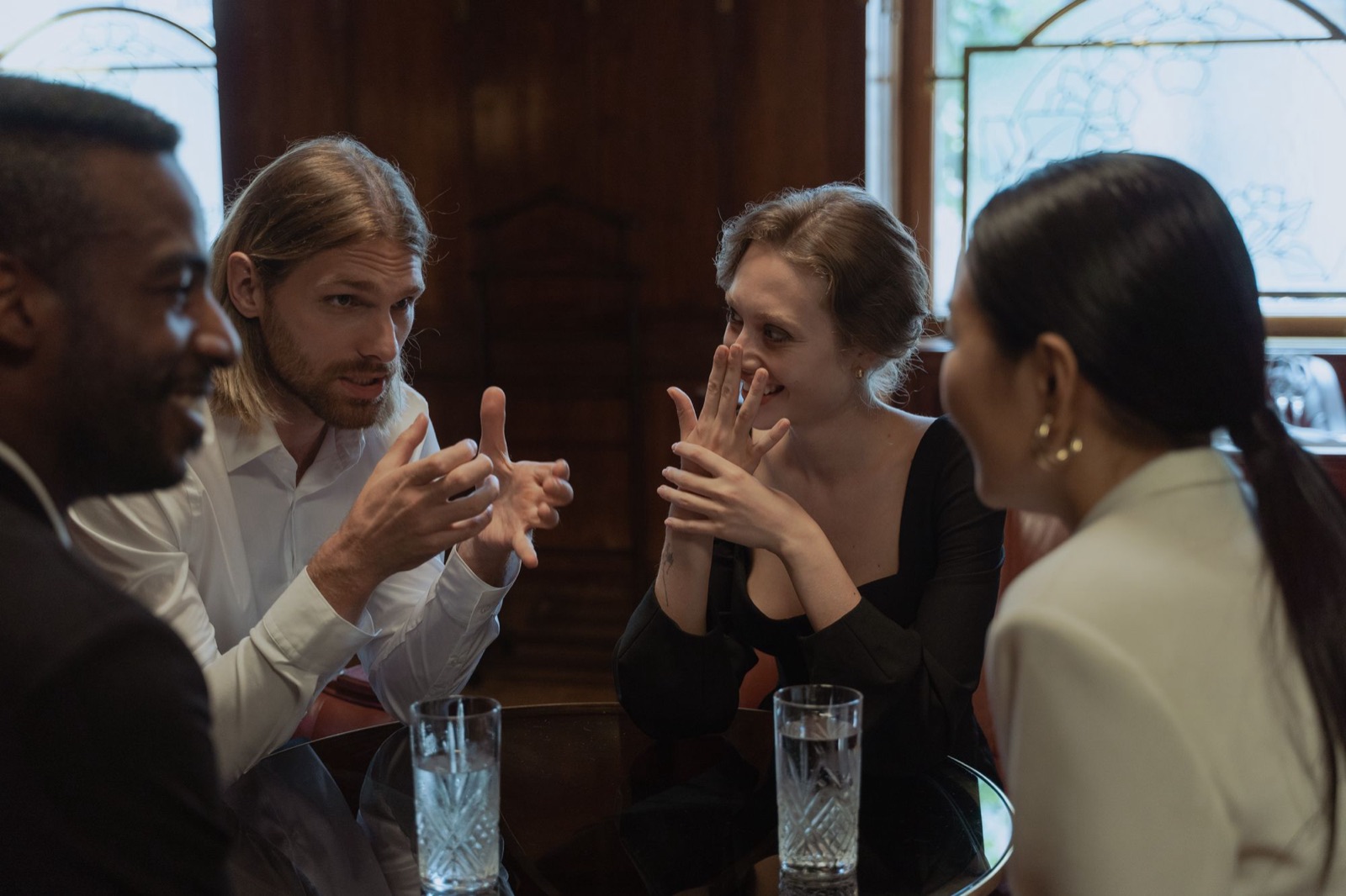 Quatre amis qui discutent et rient autour d’une table de bar
